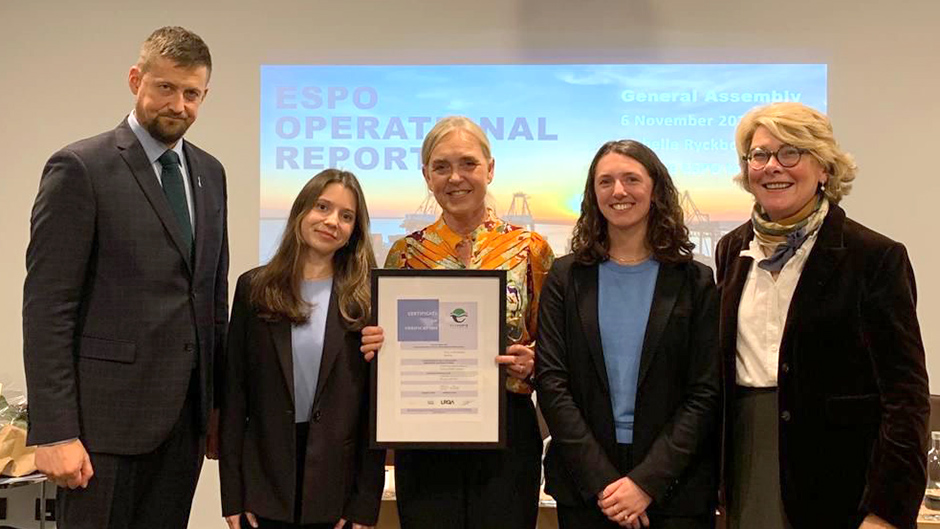 Fem personer, varav en håller i ett diplom.