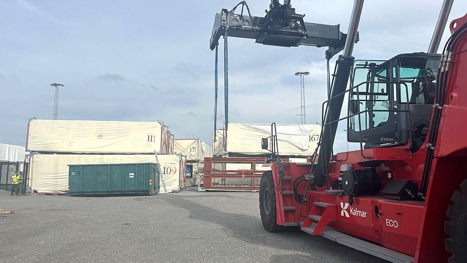 Containertruck plockar upp en husmodul från kajen i Frihamnen.